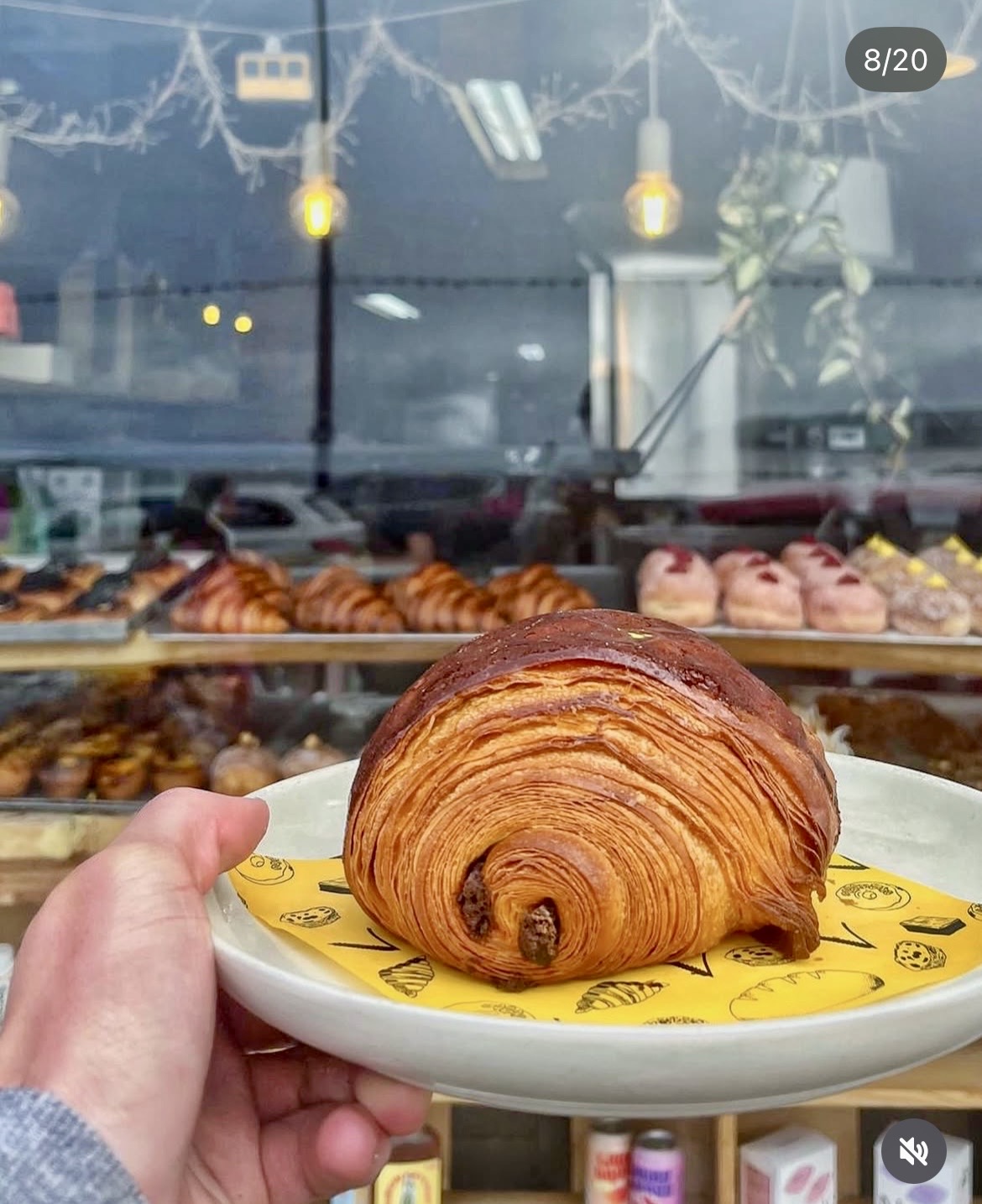 Perfectly laminated croissant held up in front of the bakery counter