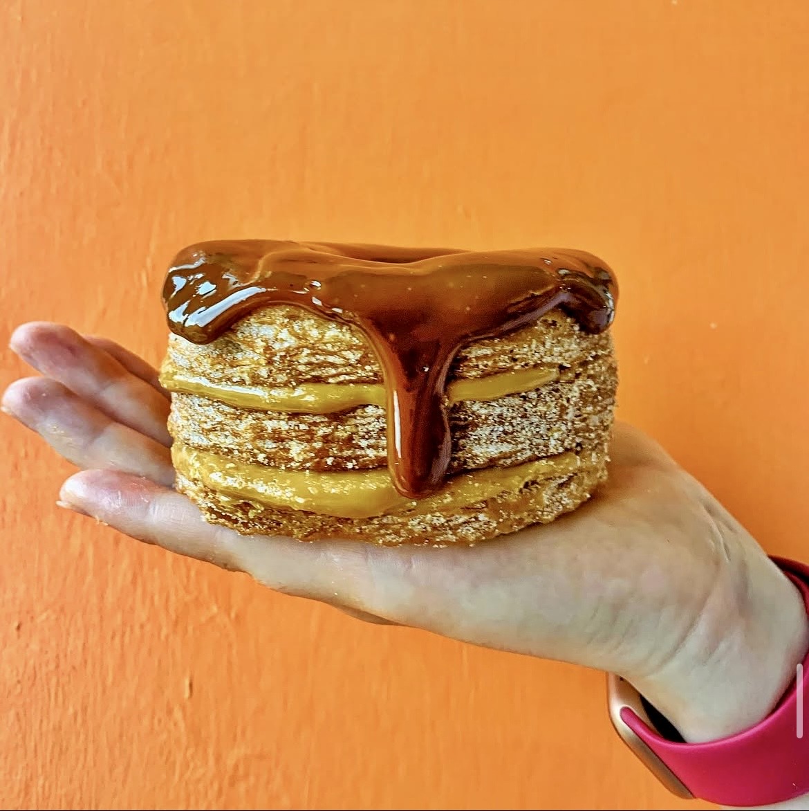 Caramel cruffin dripping with sauce held in hand